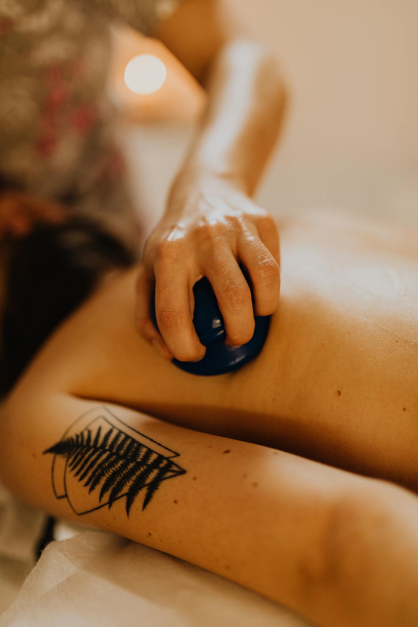 A calming massage session with a focus on relaxation using a massage cup on a tattooed back.