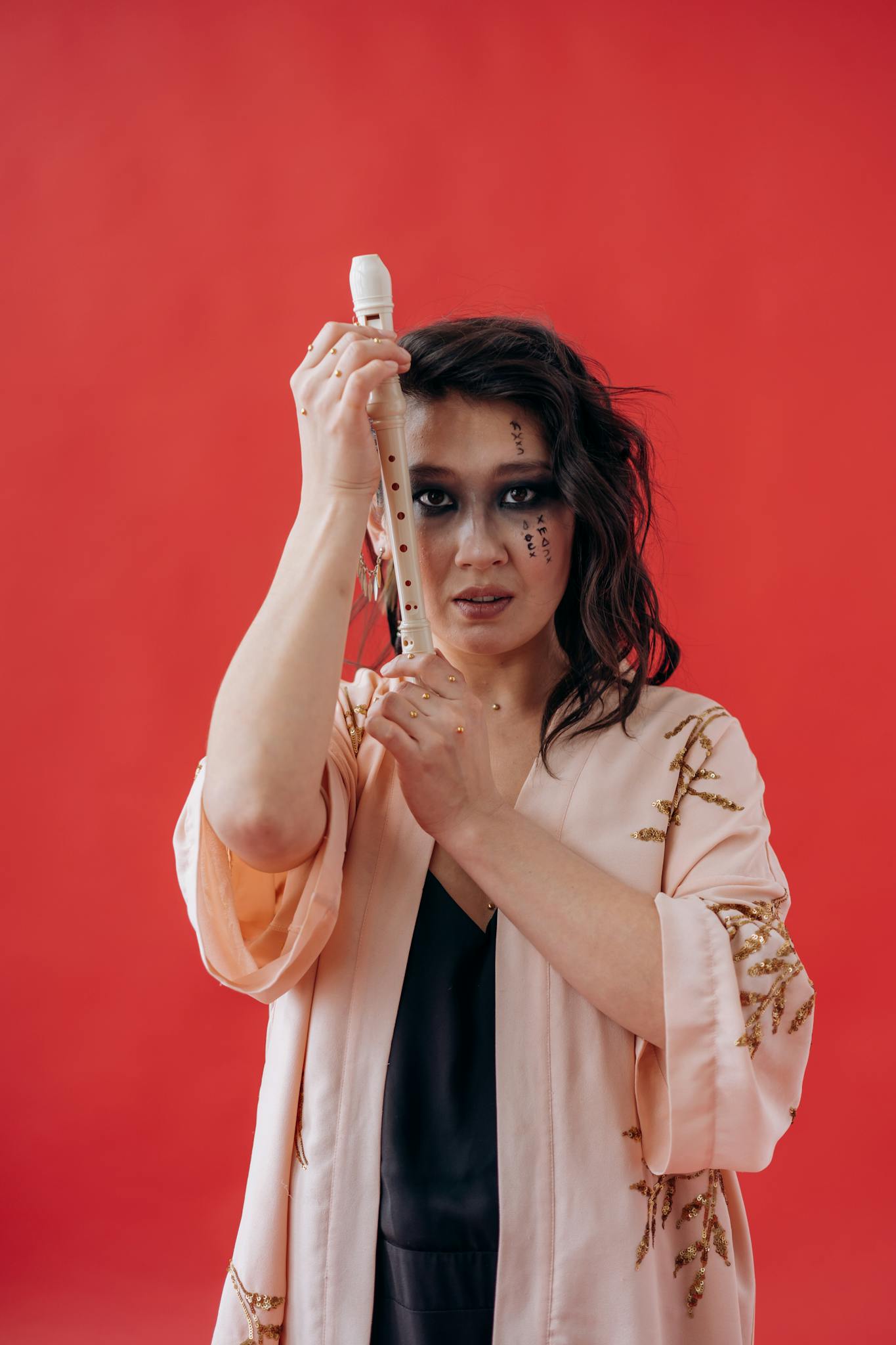 Artistic portrait of a woman in a kimono holding a flute against a vivid red backdrop. Dramatic and expressive.