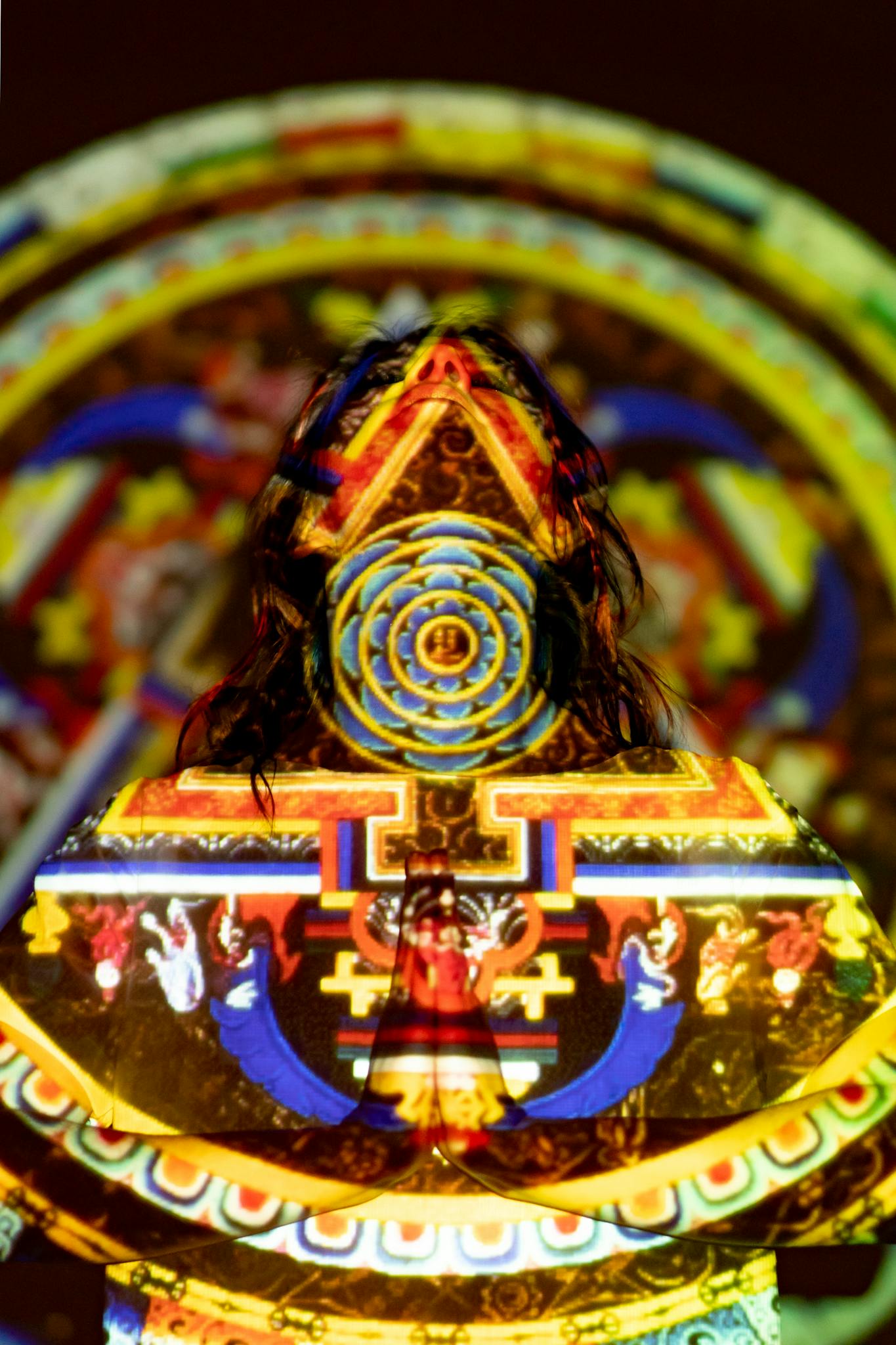 Vibrant mandala design projected on a person, evoking spiritual themes.